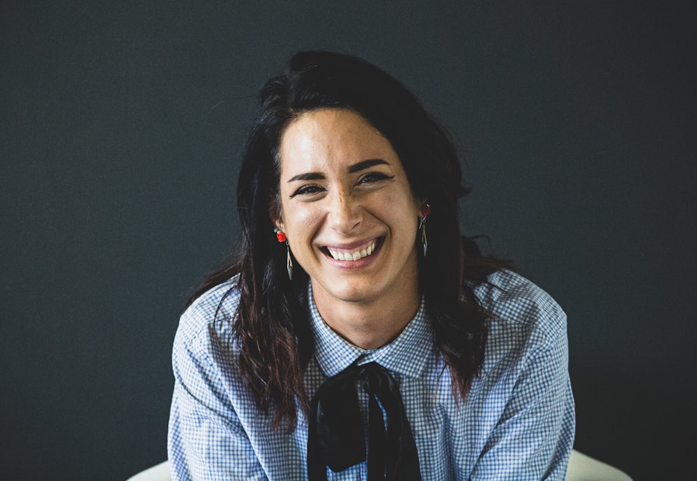 smiling woman in white and black checkered dress shirt