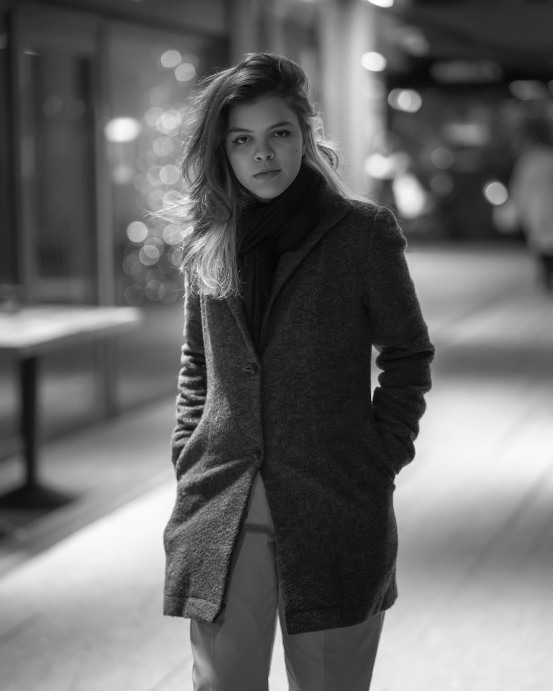 grayscale photo of woman in black coat and blue denim jeans