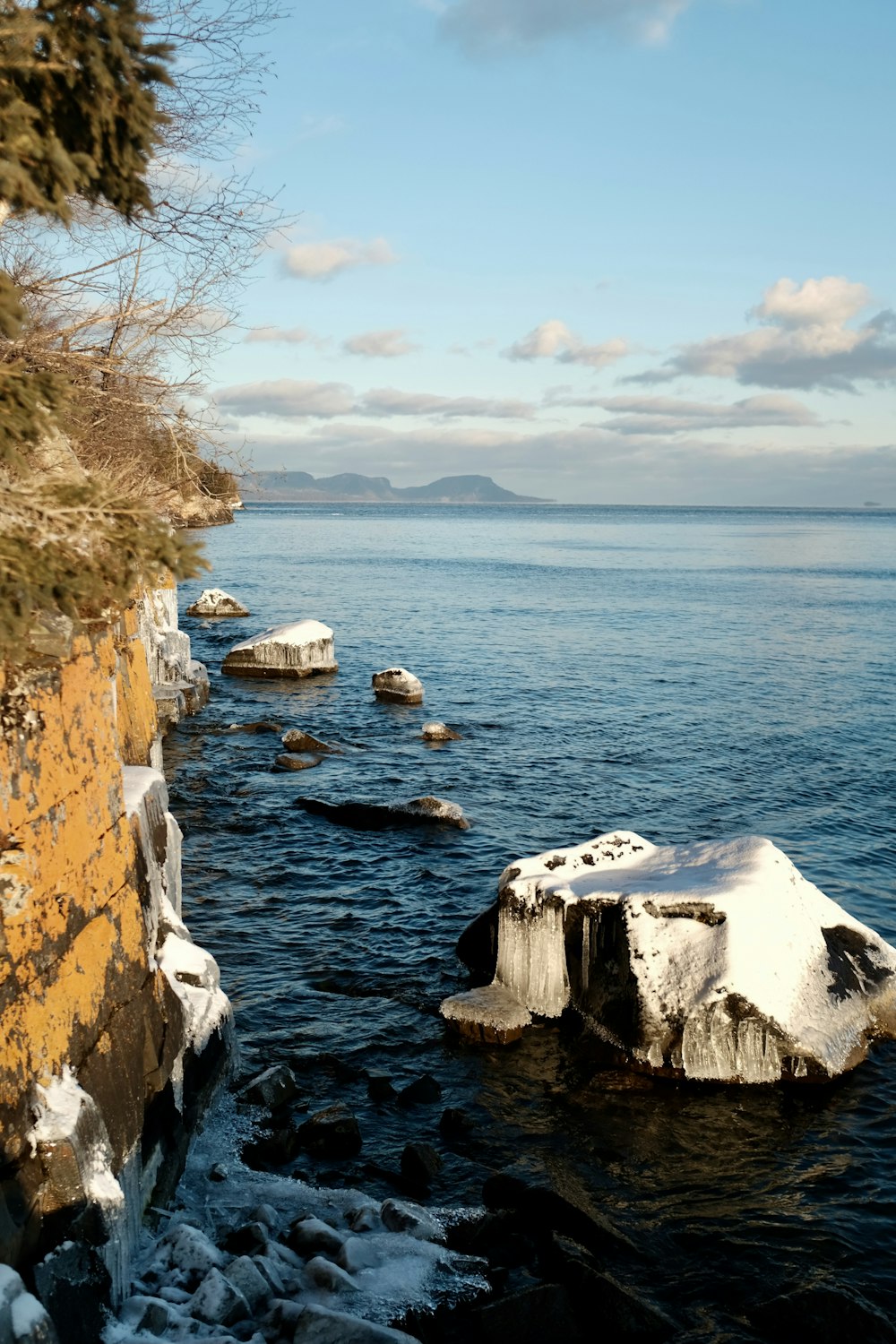 brown rocky mountain beside body of water during daytime