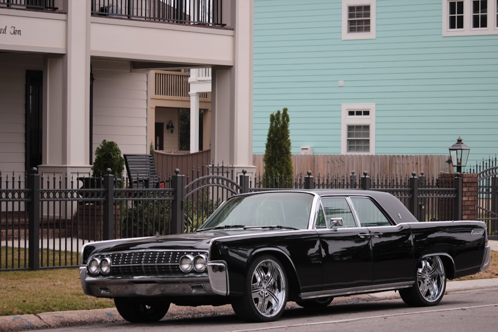 black sedan parked in front of white and pink building