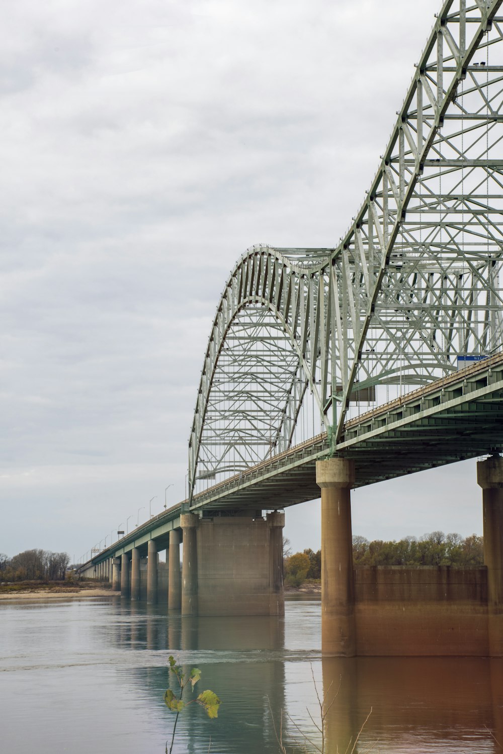 gray metal bridge over river under white clouds during daytime