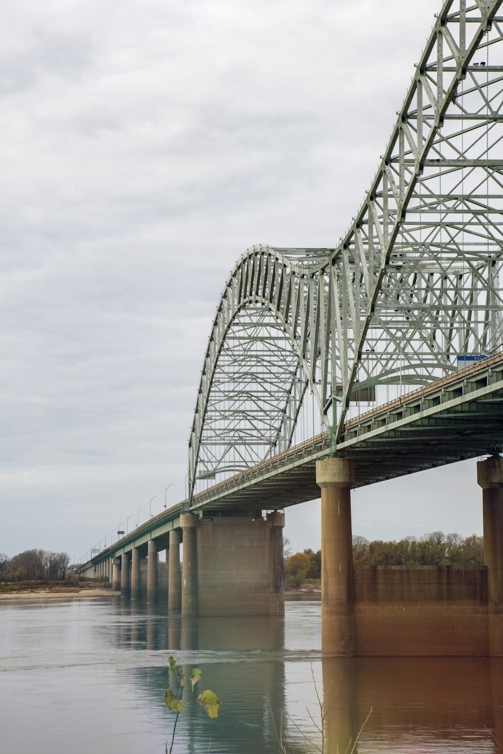 ponte de metal cinza sobre o rio sob nuvens brancas durante o dia