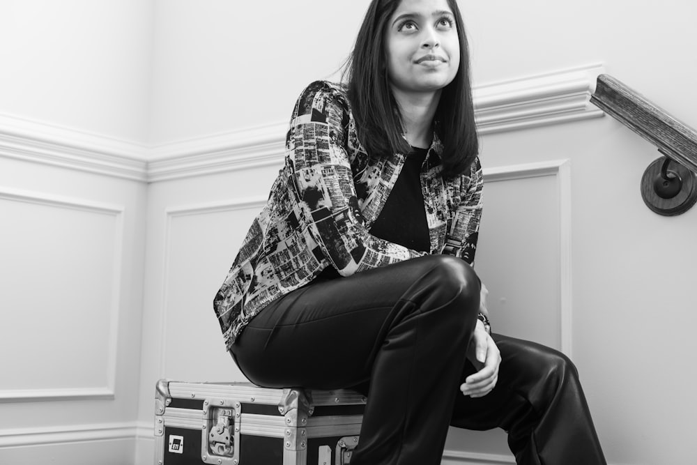 Femme en chemise à carreaux et pantalon noir assise sur une chaise