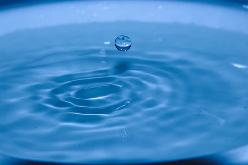 Close-up of water droplets creating concentric ripples on a glass surface.