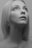 A black and white portrait of a woman with blonde hair looking upwards. Her expression is calm and thoughtful, with a soft focus on her eyes and facial features.