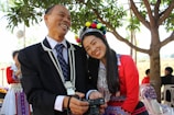A family dressed in coordinated traditional outfits posing joyfully outdoors.