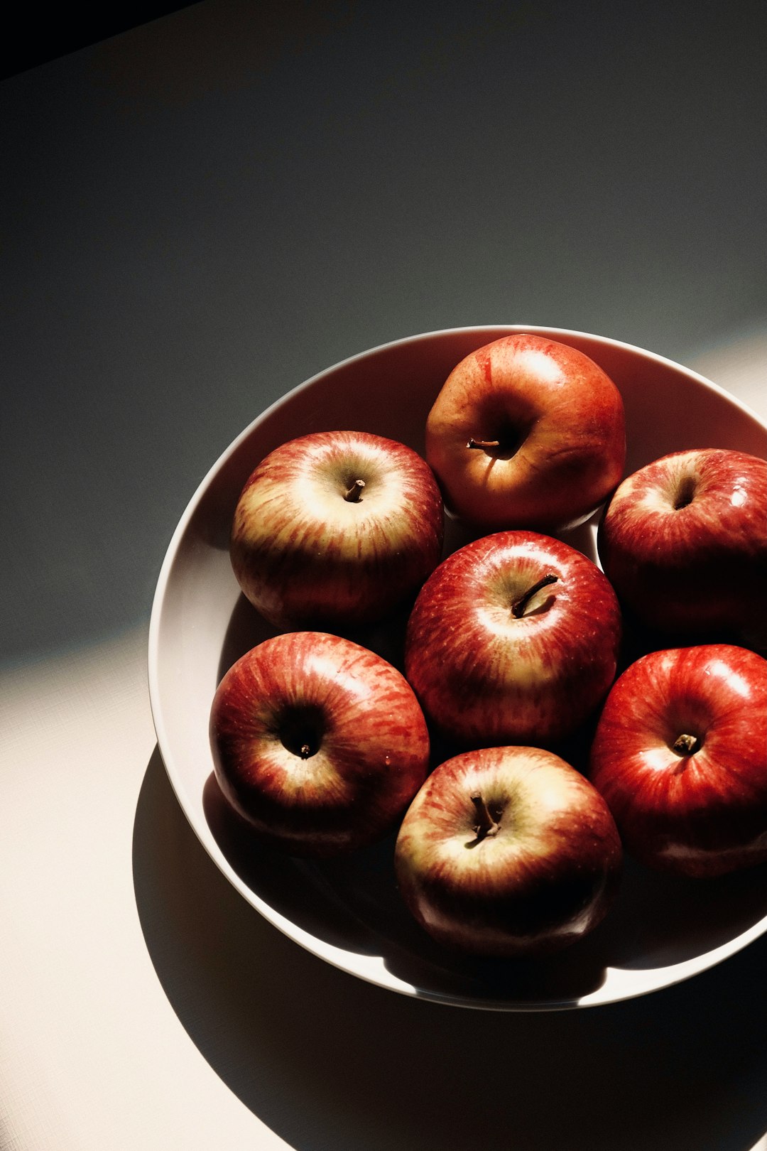 red apple fruit on white ceramic bowl