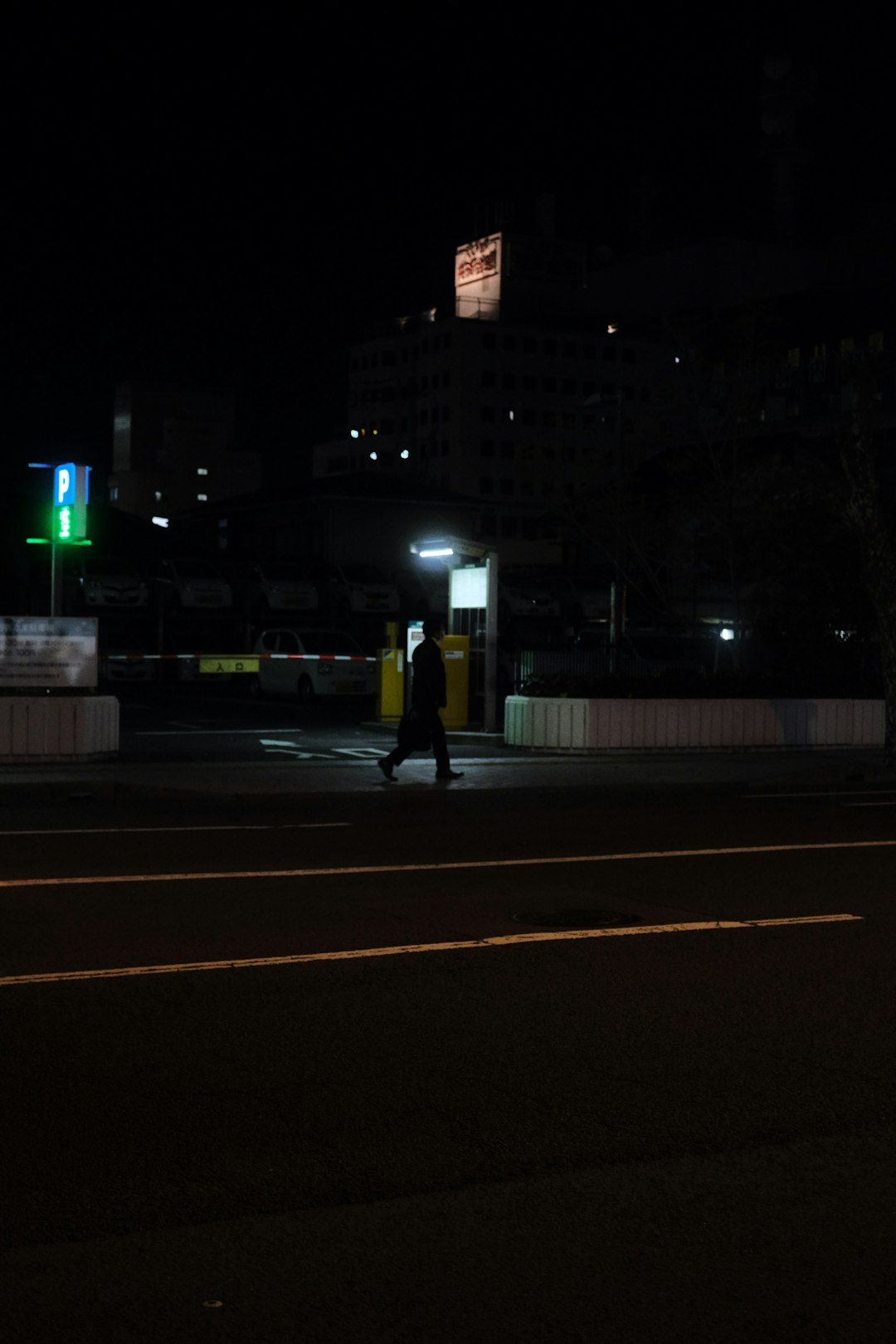 man in yellow jacket and black pants walking on sidewalk during night time