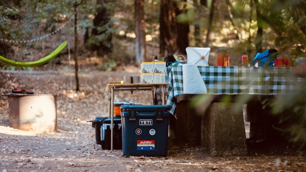 blue plastic trash bin beside green and white checkered textile