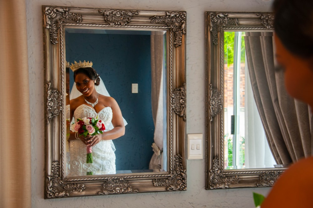 woman in white wedding dress standing in front of mirror