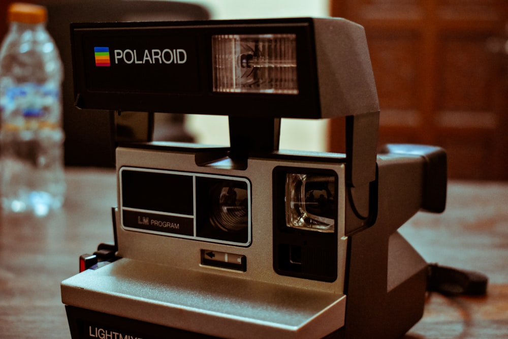 Schwarze Polaroid-Sofortbildkamera auf braunem Holztisch