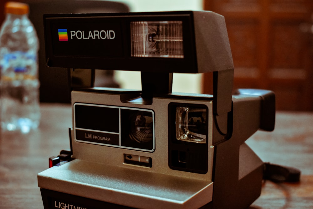 black polaroid instant camera on brown wooden table