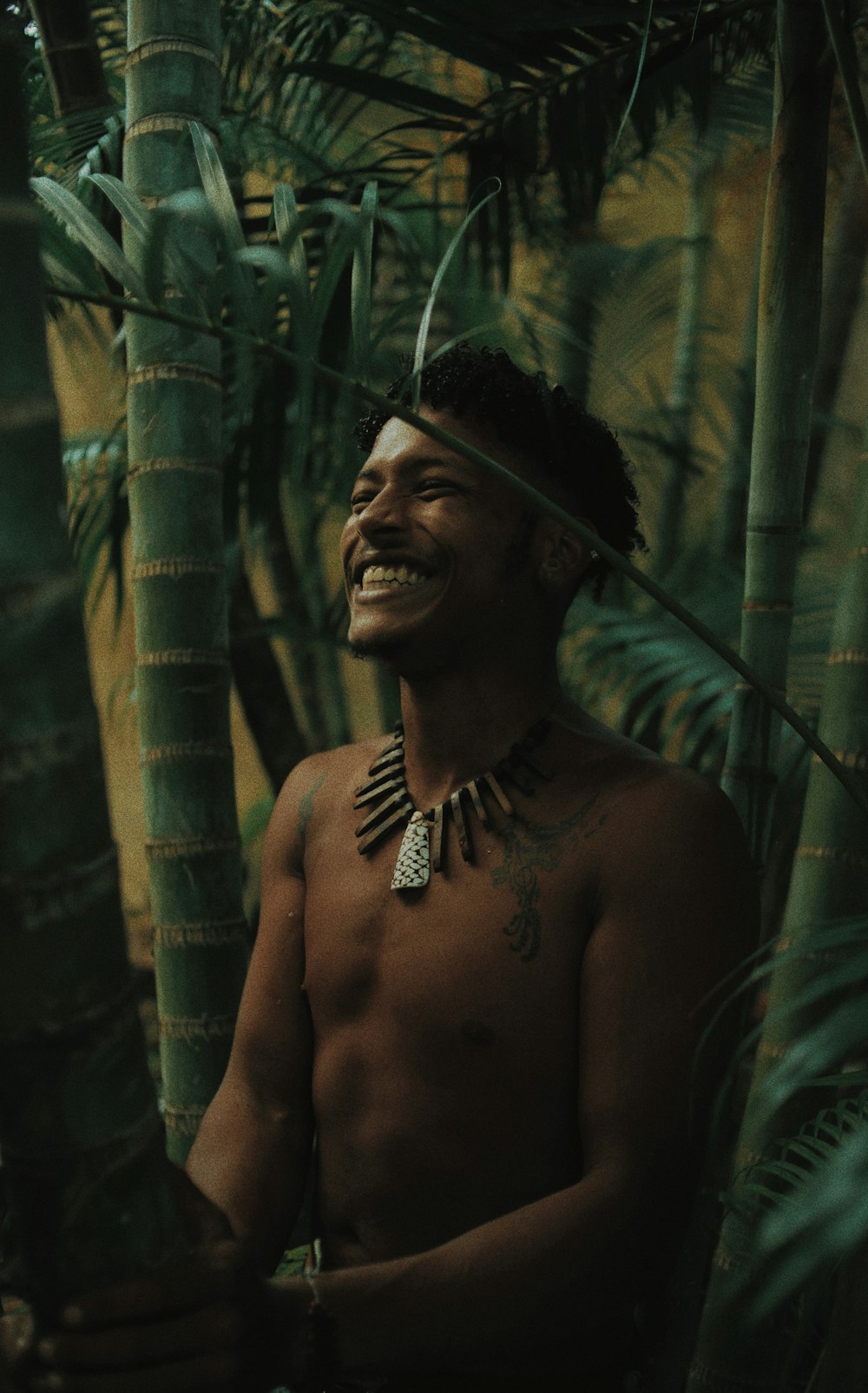 topless man standing behind bamboo tree