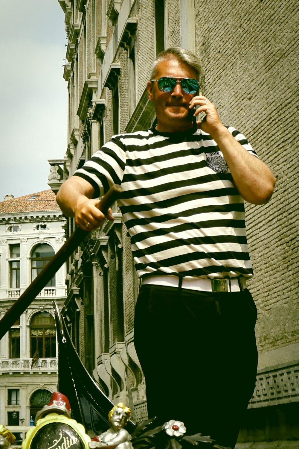 man in black and white striped shirt and black pants standing on sidewalk during daytime