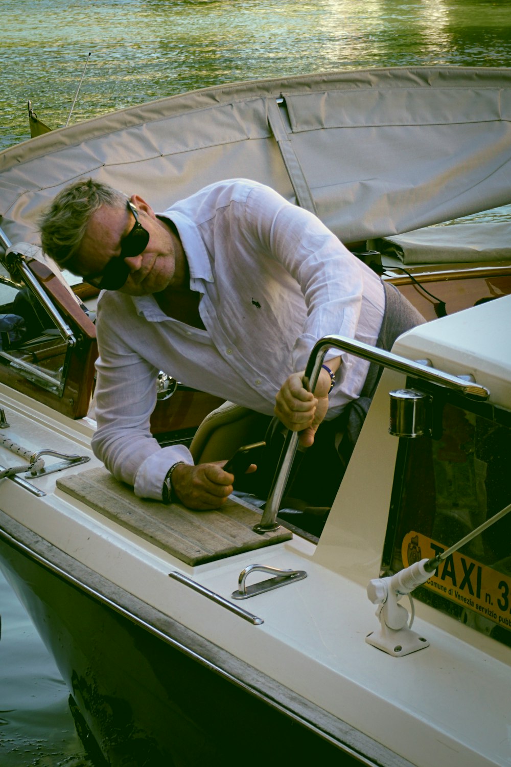 man in white dress shirt and white pants sitting on white car