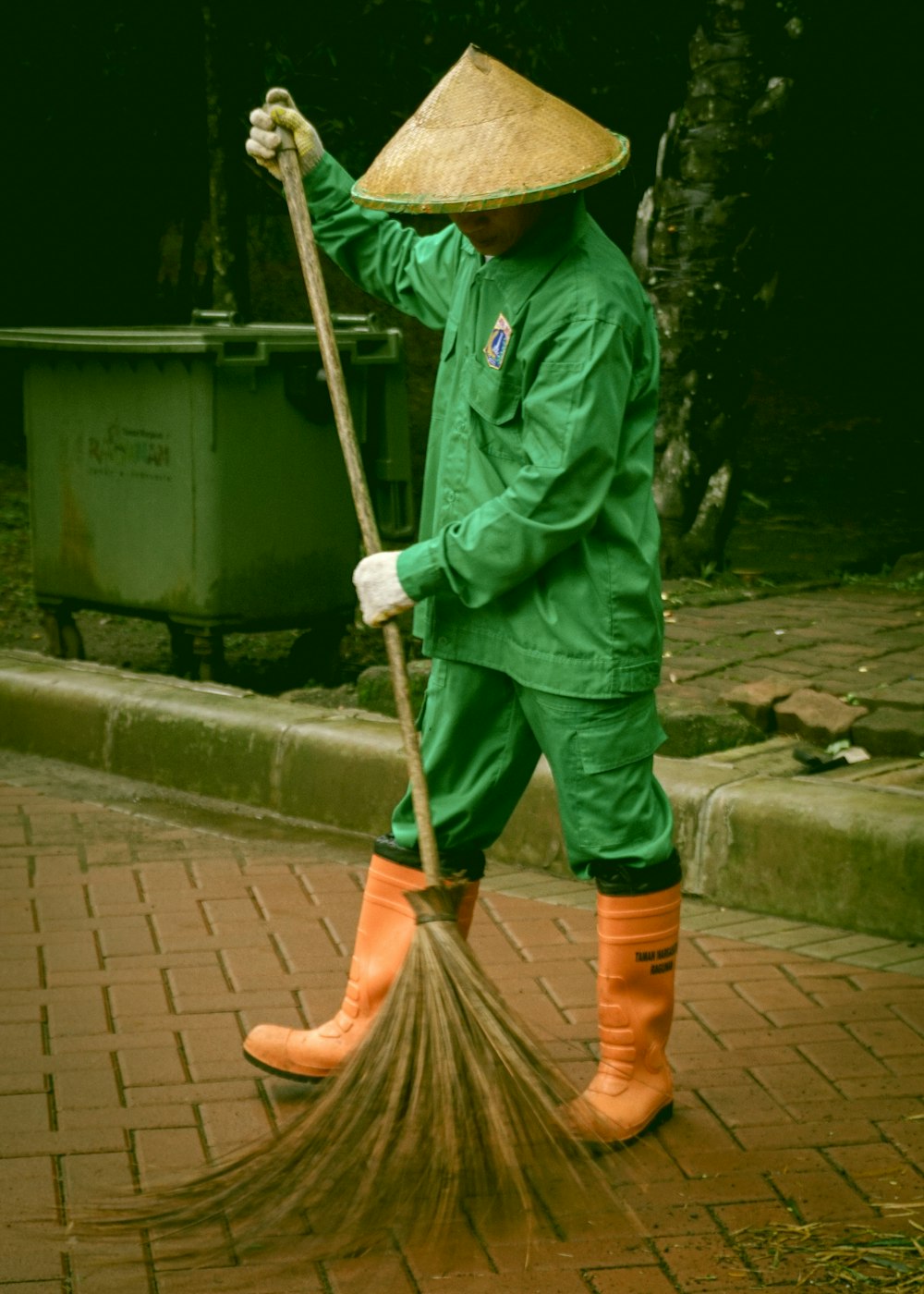 person in green jacket holding broom