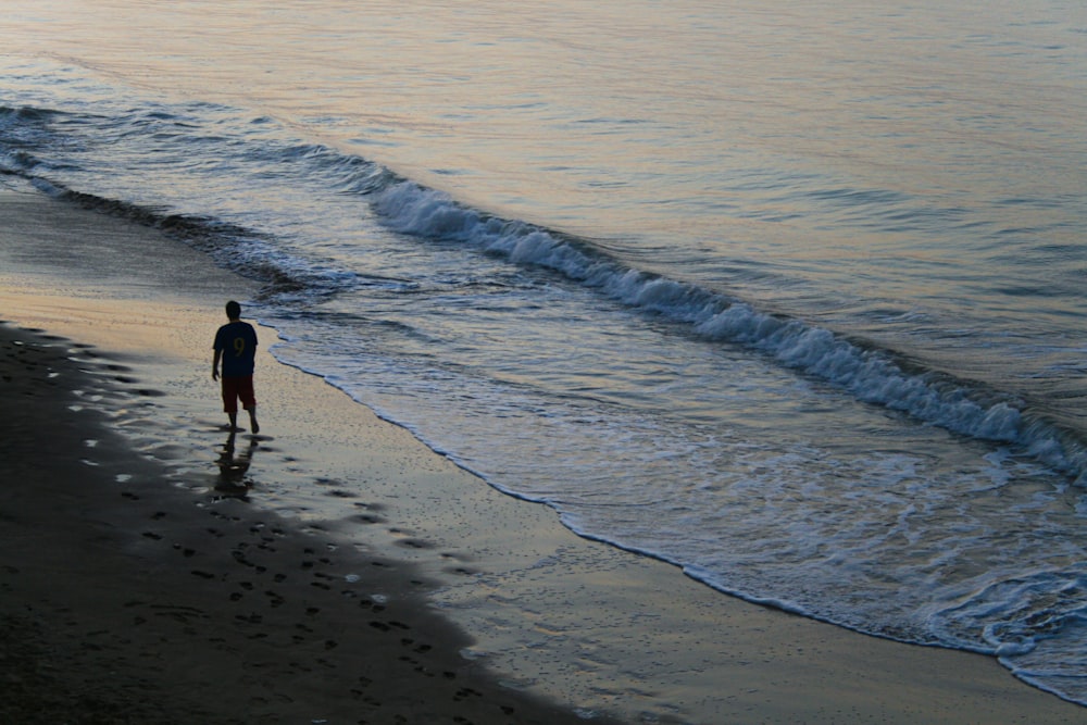 man in black jacket walking on beach during daytime