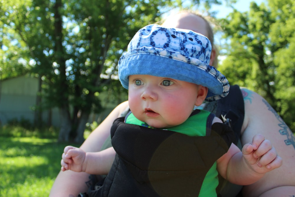 baby in blue and white floral cap and black jacket