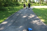 A family walking along a shaded trail surrounded by lush greenery and wildflowers.