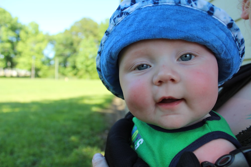 baby in green and black shirt wearing blue knit cap