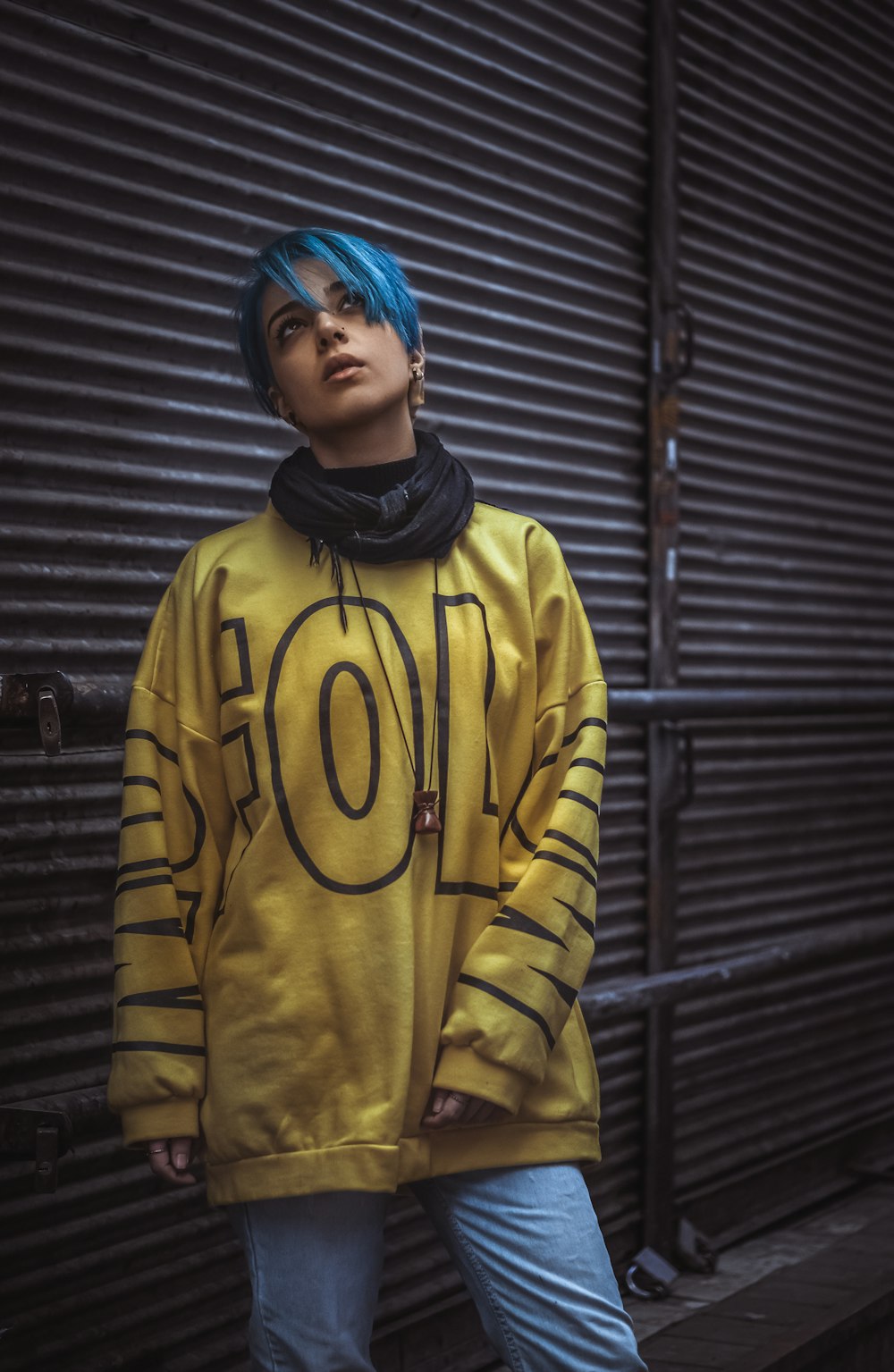 woman in yellow and black adidas hoodie standing beside black steel wall