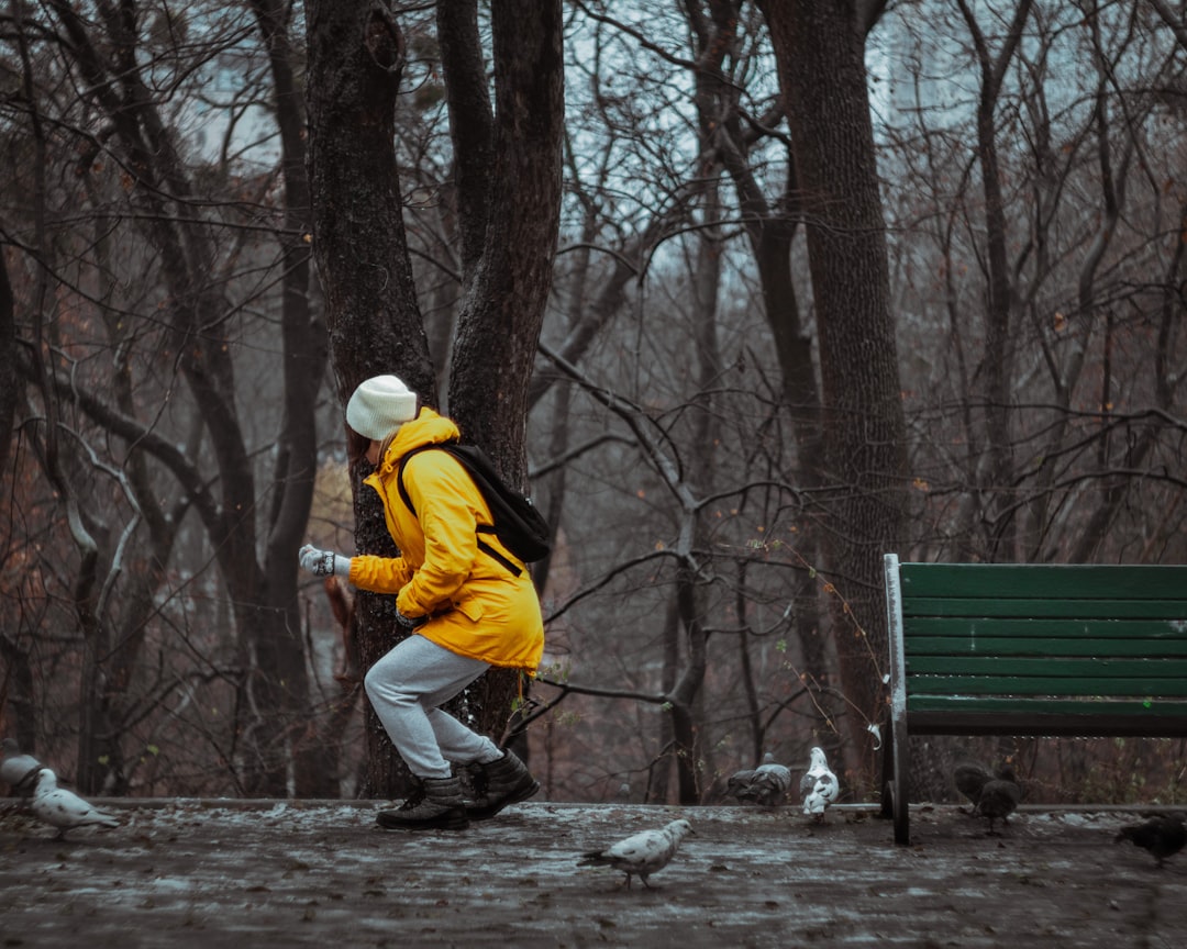 man in yellow jacket and white pants walking on forest during daytime