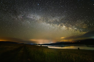 A breathtaking view of a starry night sky over a tranquil landscape.