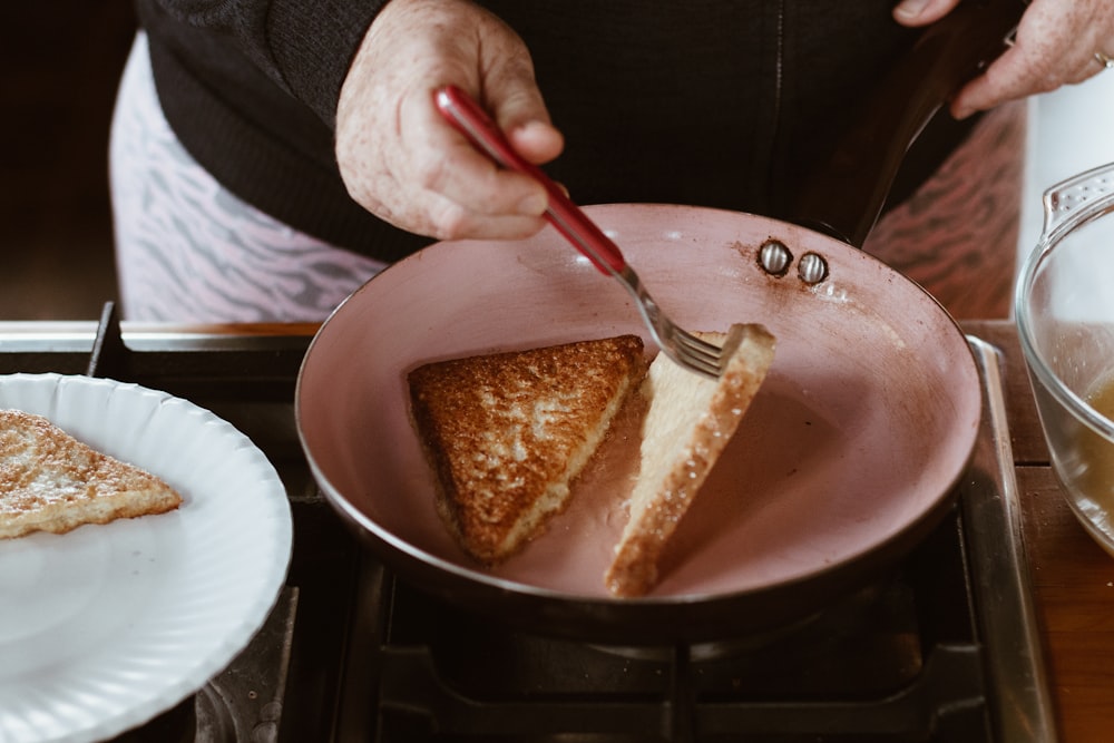 person holding red handled knife slicing cake