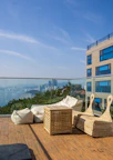 Sunlit balcony overlooking the serene cityscape with royal-themed outdoor seating.