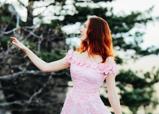girl in pink dress standing on forest during daytime