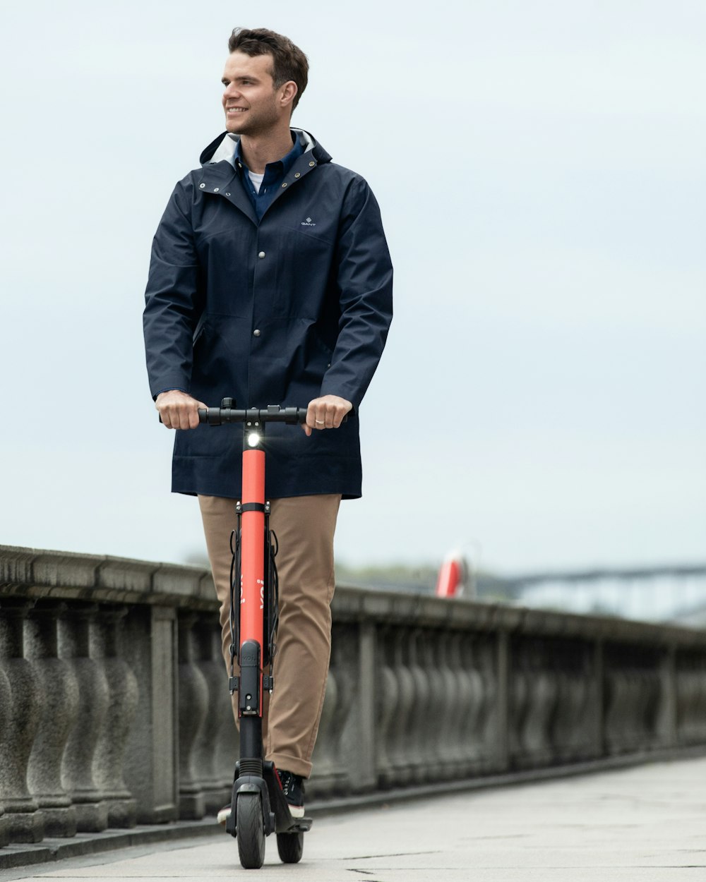 昼間、自転車の上に立っている青いジャケットとオレンジ色のズボンを着た男性