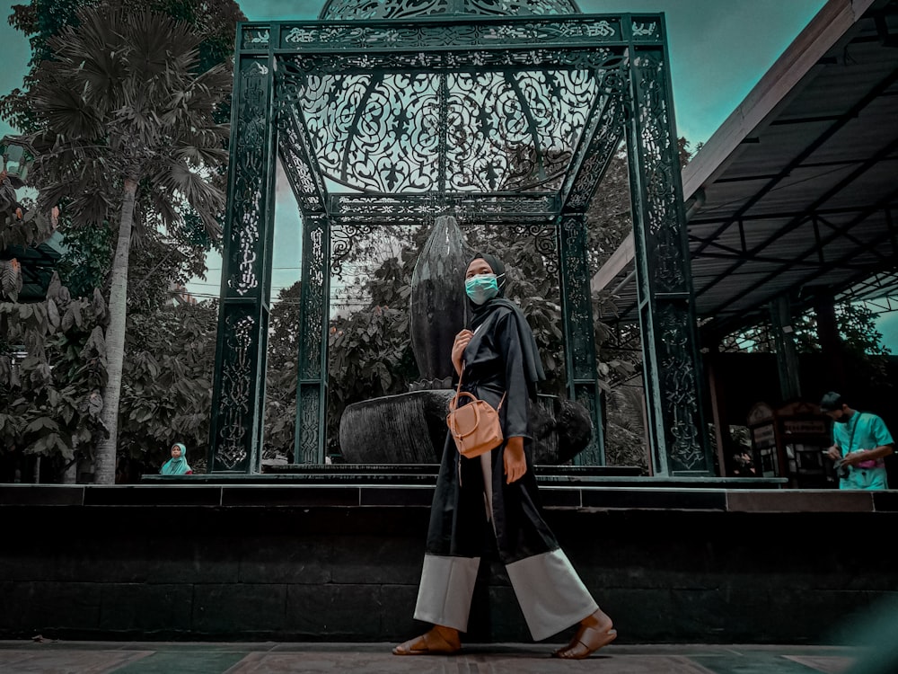 woman in black and brown dress standing in front of green wooden framed glass window