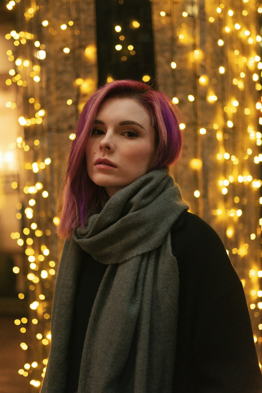 woman in black scarf standing near yellow lights