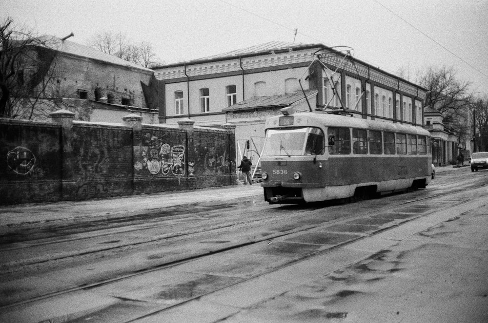 grayscale photo of tram on road near building