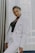 woman in white coat standing near white curtain