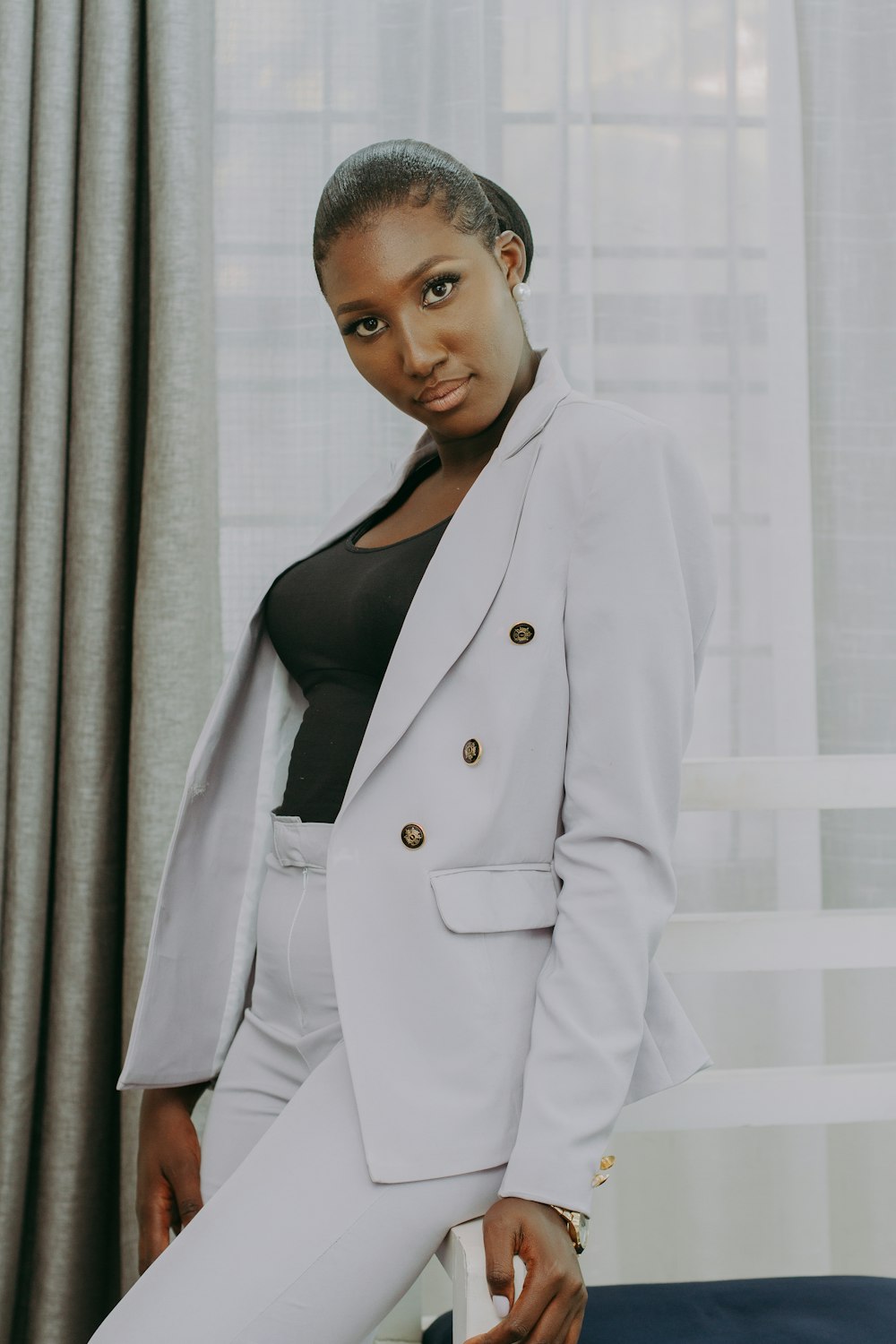 woman in white coat standing near white curtain