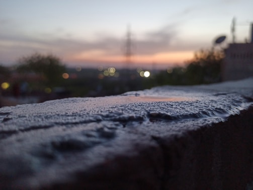 Sunset city skyline blurred in the background with a Lumina Apparel hoodie in sharp focus.