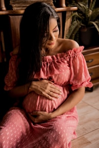 woman in pink dress sitting on brown wooden chair