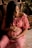 woman in pink dress sitting on brown wooden chair