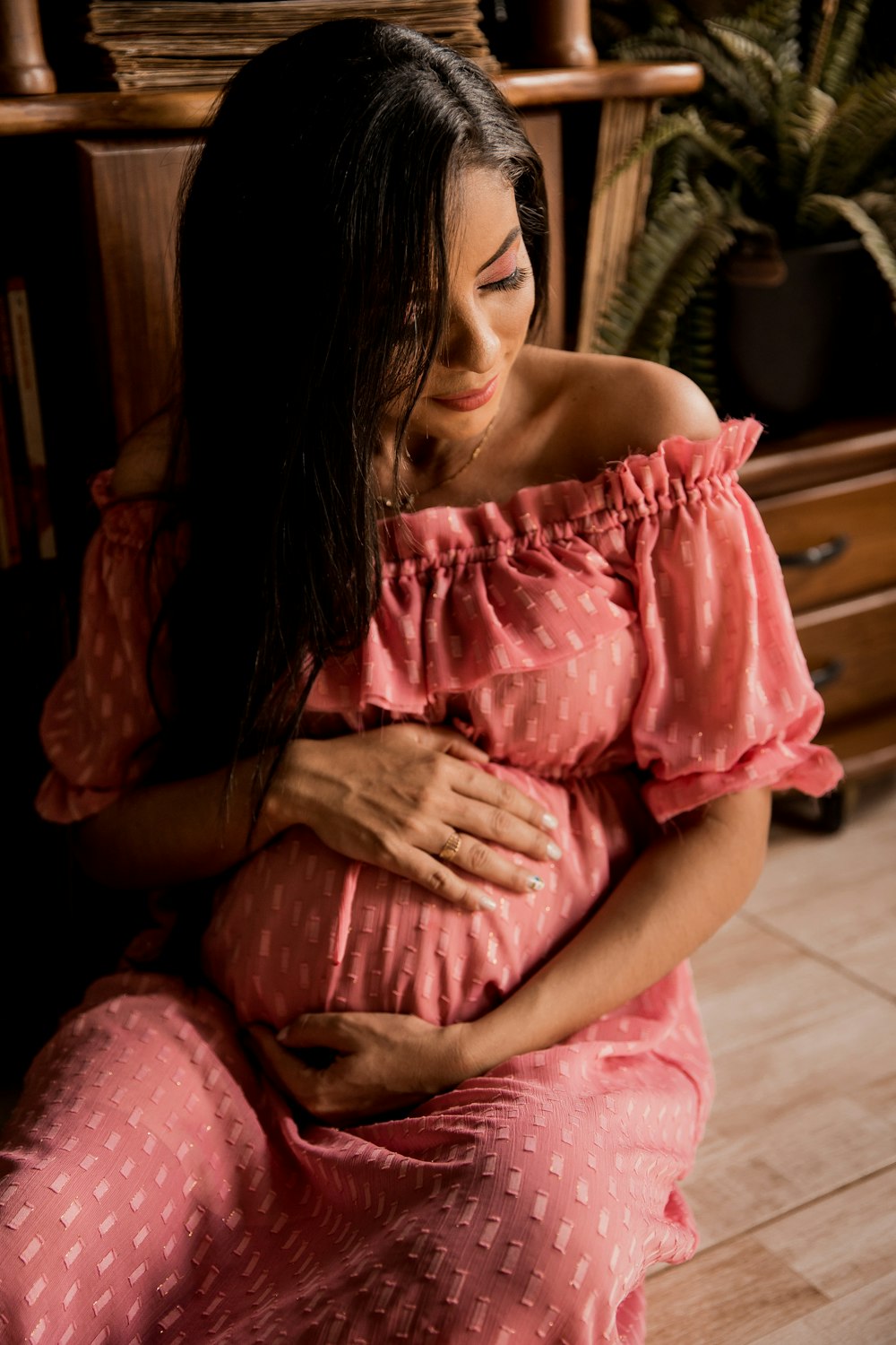 woman in pink dress sitting on brown wooden chair