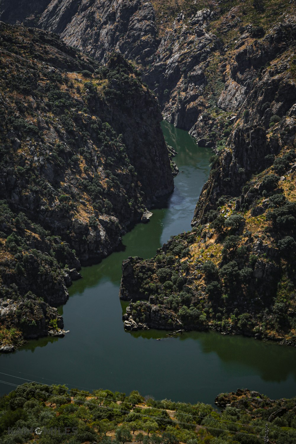 Montaña rocosa verde y marrón al lado del río durante el día