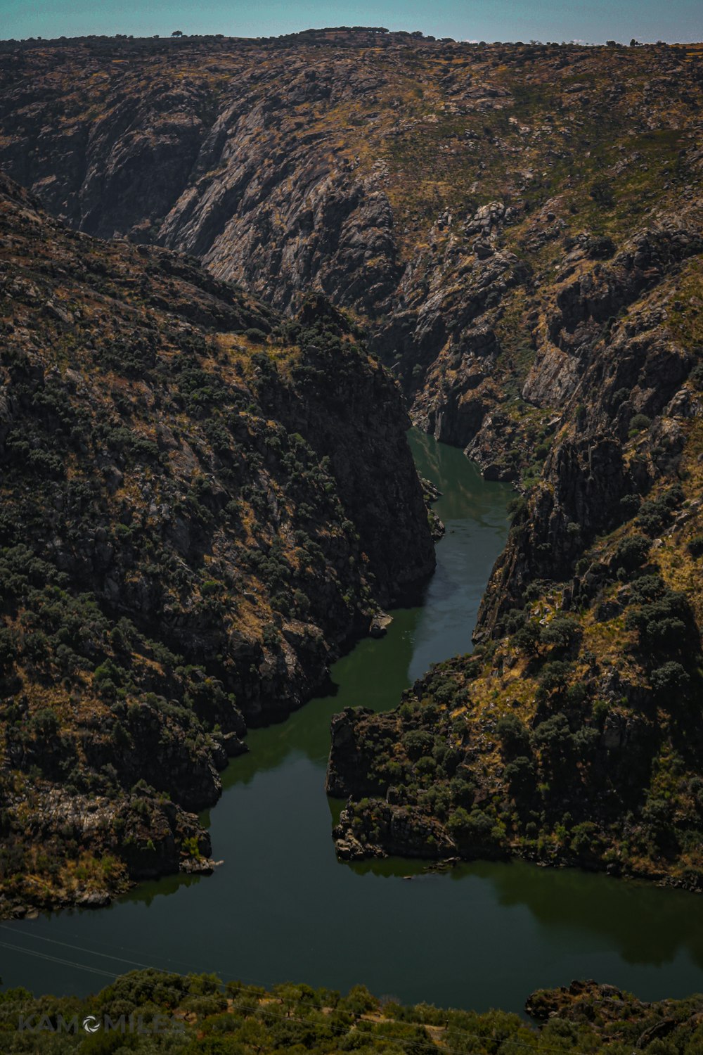 Montañas verdes y marrones junto al río durante el día