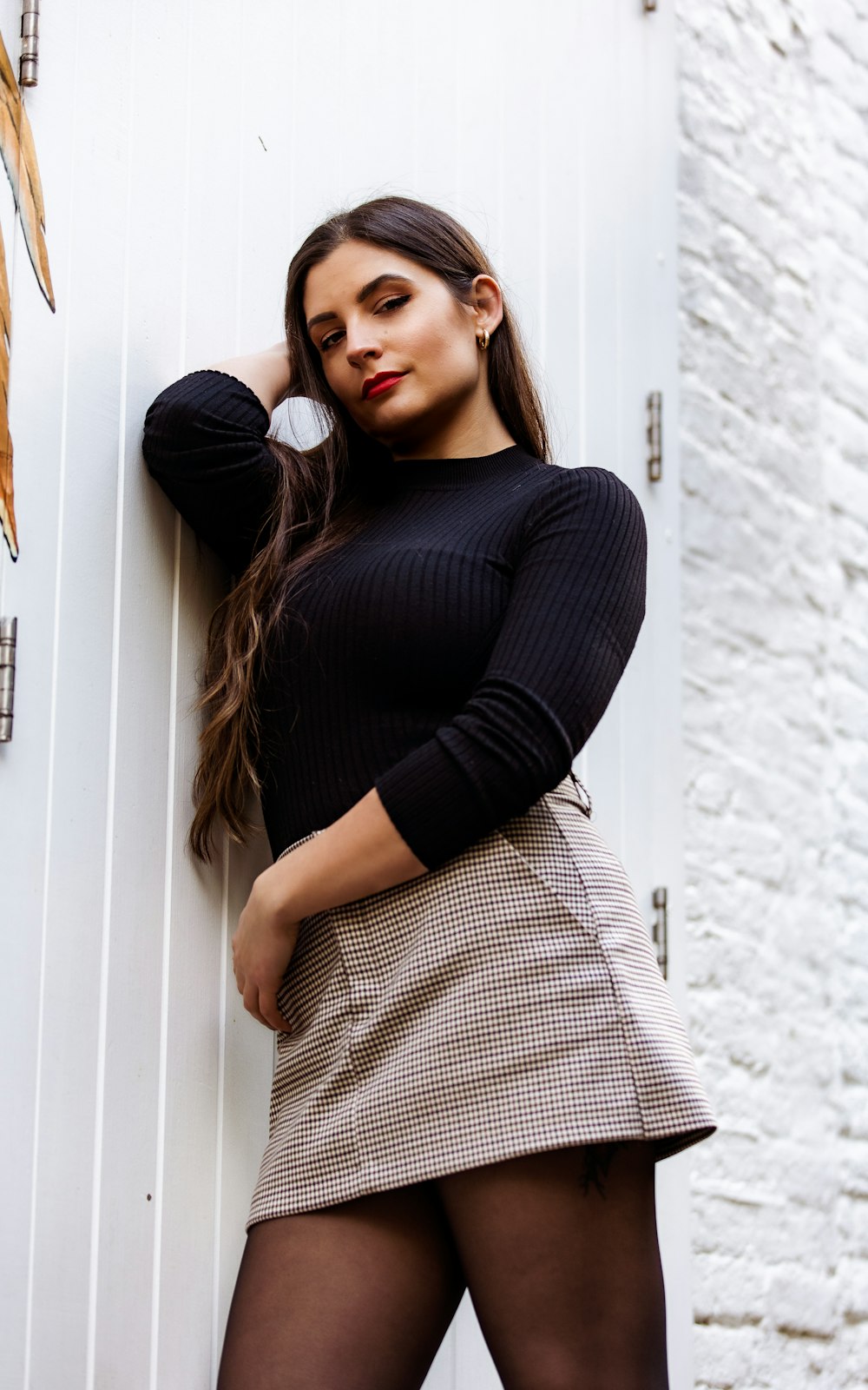 woman in black long sleeve shirt leaning on white wall