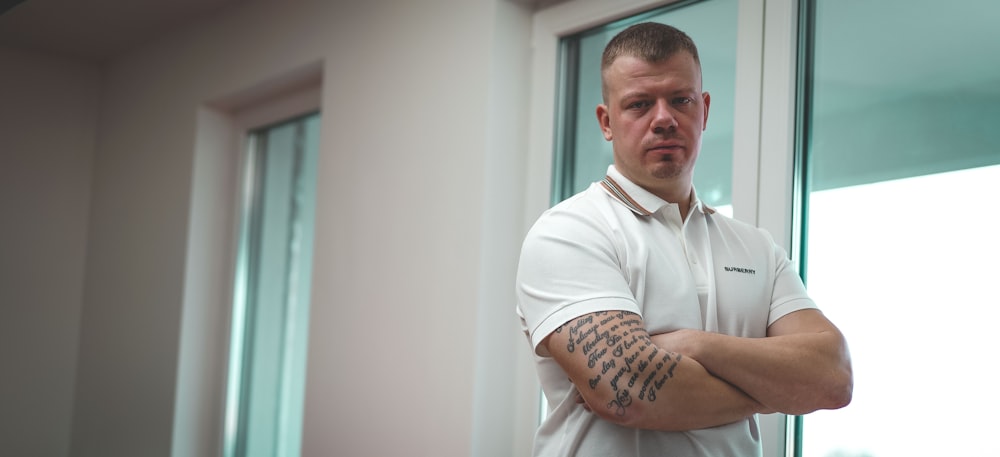 man in white polo shirt standing near white wall