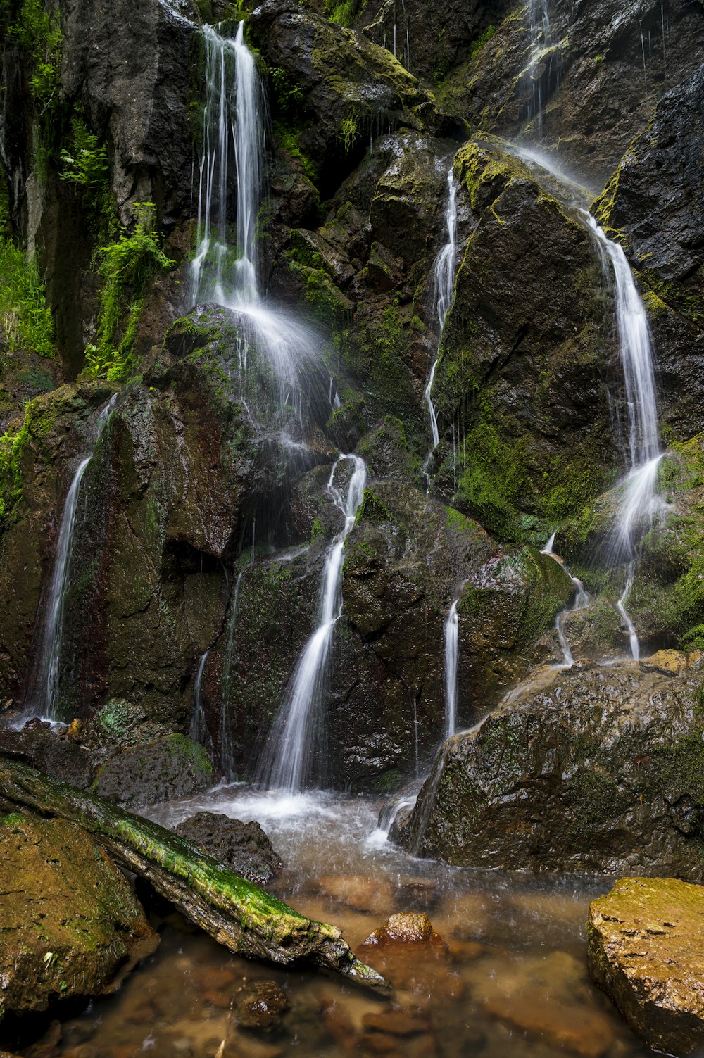 water falls on brown rocky mountain