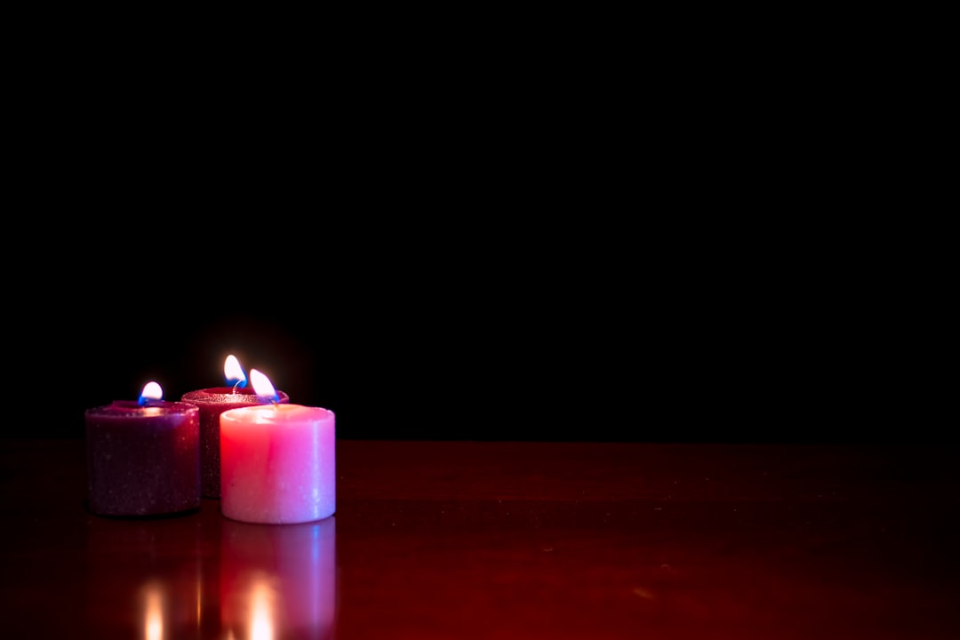 purple lighted candle on brown wooden table