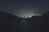 A dramatic silhouette of a lone figure standing before a glowing celestial portal at dusk.