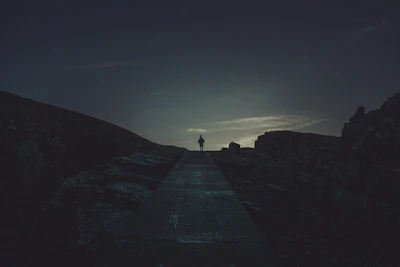 A dramatic silhouette of a lone figure standing before a glowing celestial portal at dusk.