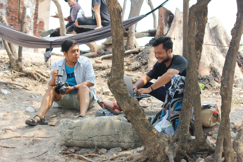 man in white t-shirt sitting on rock