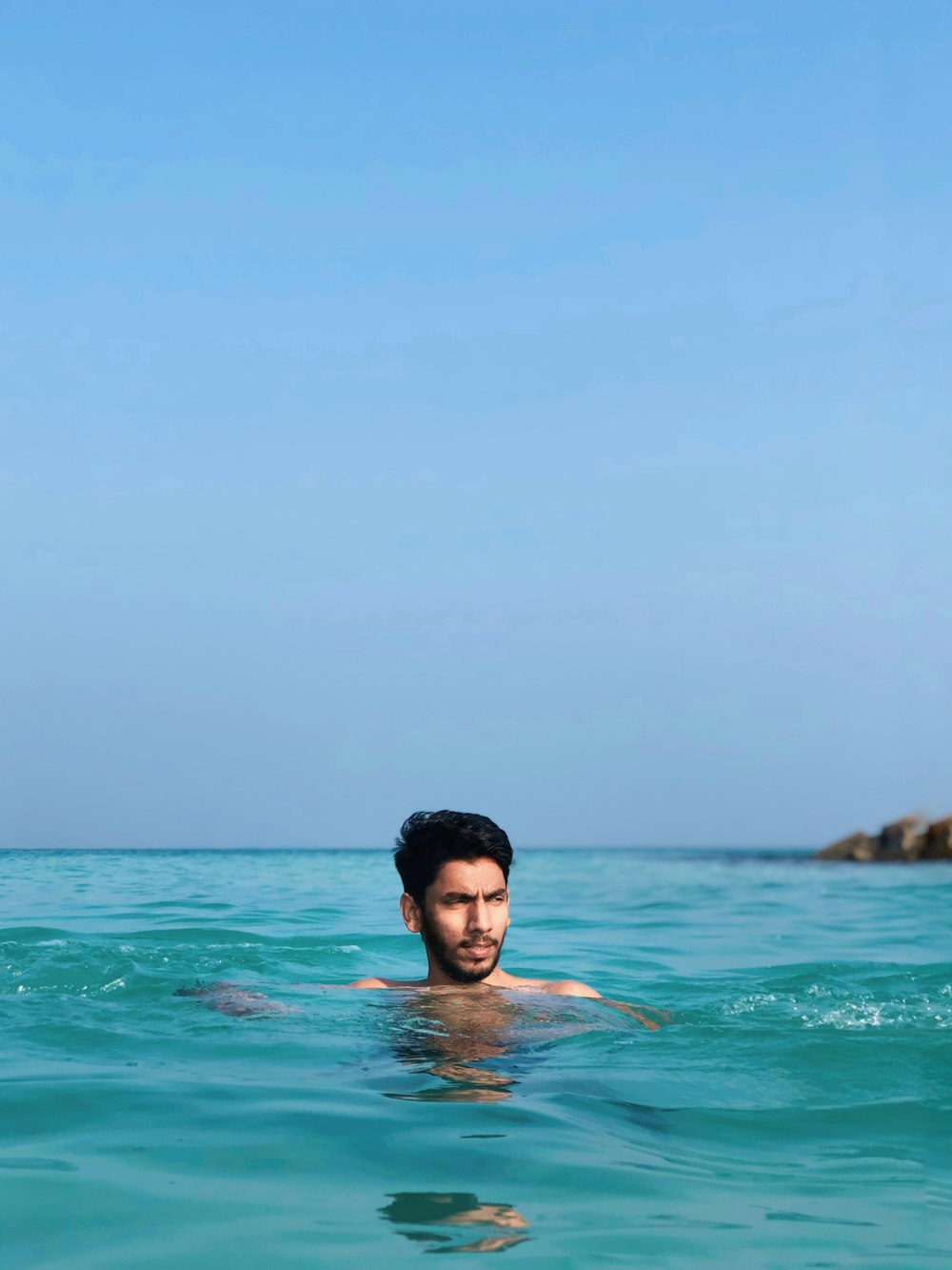 man in blue swimming trunks in sea during daytime